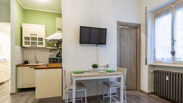 Una cocina compacta con comedor, un televisor montado en la pared y una ventana con vistas.