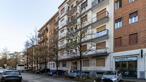 A multi-story residential building with balconies, parked cars, and a storefront. - Feel Good - Downtown Varese - Apartment for 2 people - Free Wi-Fi - By Guestaly (Varese)