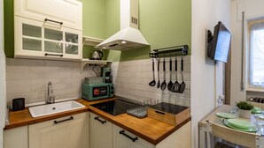 Una cocina con un lavamanos blanco, una estufa, un microondas y un tostador. Hay armarios con puertas de vidrio y una campana extractora sobre la estufa.