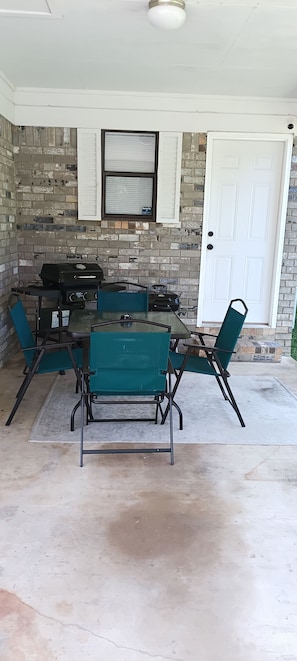 An outdoor patio with a brick wall, a grill, and a table with chairs. - 3-bedroom house in serene Hot Springs with cool AC (Hot Springs)