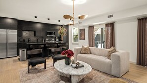 A modern living room with a sofa, coffee table, and chairs. There is a kitchen area with a refrigerator, microwave, and dining set. - Resort-Style 4BR Ensuites •Slps11 •Pool&Spa •Gate (Houston)