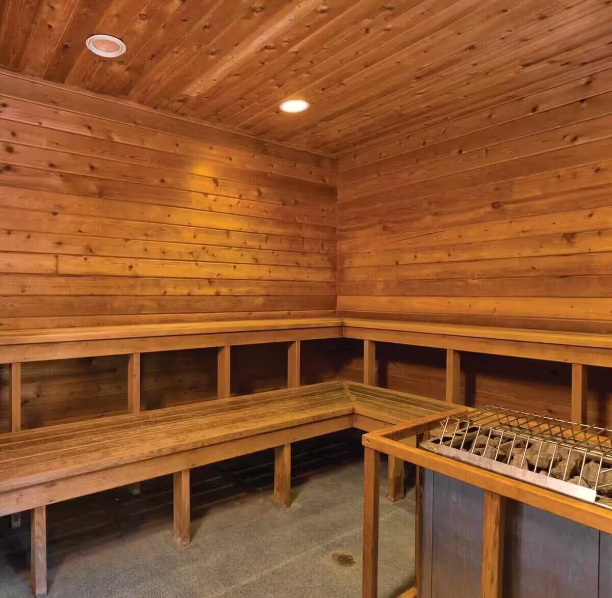 Una sauna con panche in legno e un portasciolato in metallo.