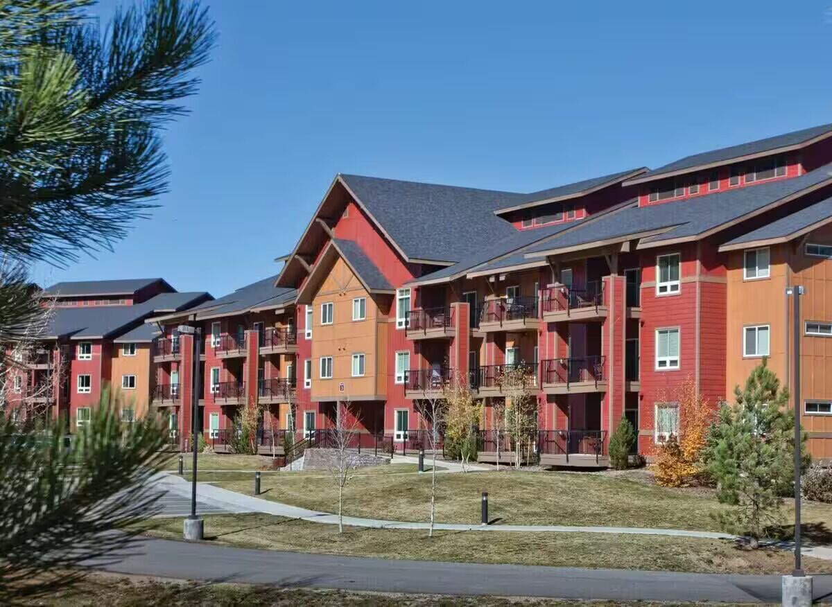 A multi-story residential building with balconies, a central courtyard, and a clear sky.