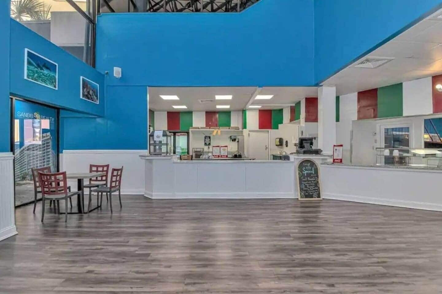 A restaurant with a blue wall, a counter, and a chalkboard menu.
