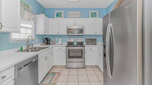 Una cucina moderna con mobili bianchi, elettrodomestici in acciaio inossidabile e una parete di colore blu.