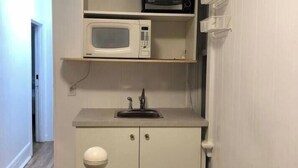 Une petite cuisine équipée d’un four à micro-ondes, d’un évier et d’un placard.