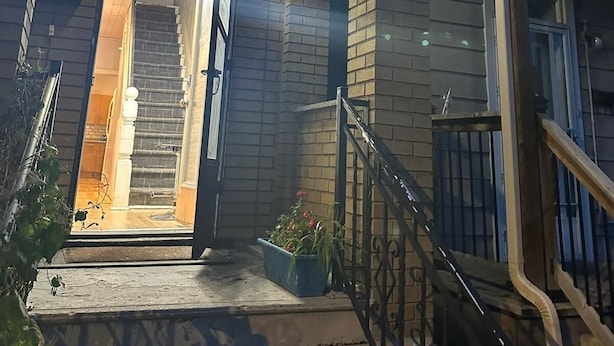 Un immeuble résidentiel avec une entrée bien visible, un escalier et un petit espace de porche agrémenté d’un pot de fleurs.