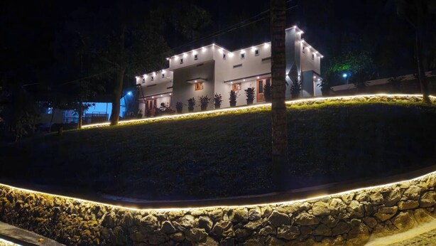 A modern two-story building with a stone retaining wall and a well-lit pathway. - Elove Resort Private Hideaway on 6 Serene Acres (Thamarassery)