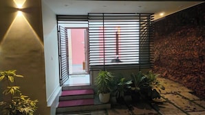 A staircase with a red carpet leading to a room with a pink wall and a window with horizontal blinds. - Elove Resort Private Hideaway on 6 Serene Acres (Thamarassery)