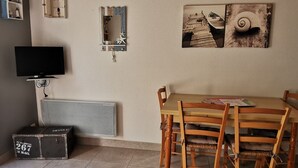 A room with a wooden table and chairs, a television, a radiator, and a small cabinet. - Practical house, pets welcome - 6 guests (La Tranche-sur-Mer)
