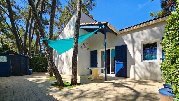 A building with a covered patio area, a small table, and a blue door. - Practical house, pets welcome - 6 guests (La Tranche-sur-Mer)