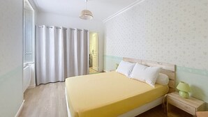 Quarto com cama, cortinas, mesa de cabeceira, luminária e porta.