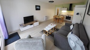 Een knus woongedeelte met een bank, televisie, eettafel en kitchenette.