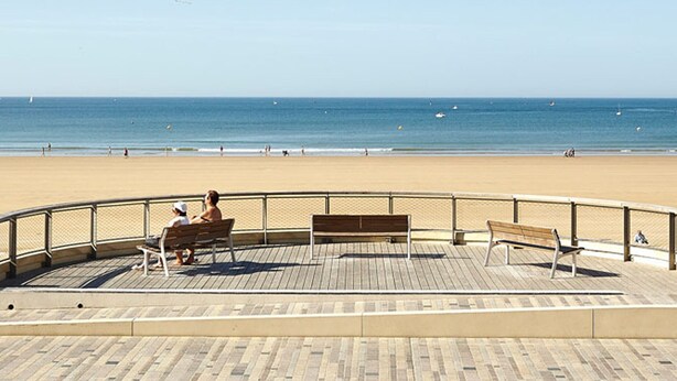 Een strandboulevard met bankjes en een hekwerk.