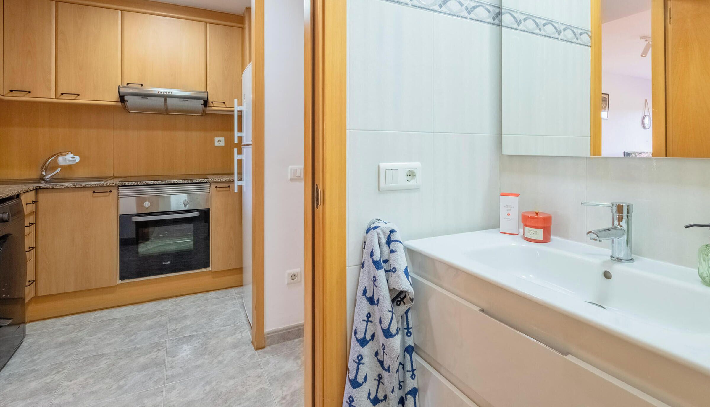 Een keuken met houten kastjes, een inbouwoven en een roestvrijstalen afzuigkap.