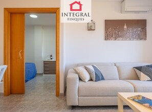 A living room with a sofa, a coffee table, and a cityscape painting on the wall. - Apartment with AC and parking, mountain view (Palamós)