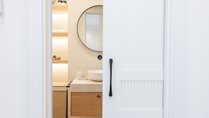 A modern bathroom with a white vanity, a round mirror, and a wooden cabinet. - Apartment with private terrace - 4 guests (Málaga)