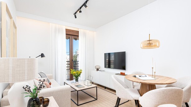A modern living room with a sofa, coffee table, and chairs, a dining area with a table and chairs, a TV mounted on the wall, and a balcony with curtains. - Apartment with private terrace - 4 guests (Málaga)