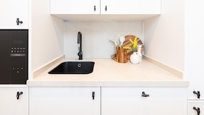 A kitchen with a black sink, white cabinets, and a countertop with kitchen utensils. - Apartment with private terrace - 4 guests (Málaga)