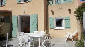 A building with multiple windows and doors, some with shutters, and a patio area with outdoor furniture. - Comfortable villa, parking, pets welcome - 6 guests (Gruissan)