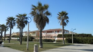 A building with a tiled roof, surrounded by palm trees and a clear blue sky. - Comfortable villa, parking, pets welcome - 6 guests (Gruissan)
