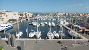A marina with numerous boats docked, a pedestrian walkway, and buildings in the background. - Comfortable villa, parking, pets welcome - 6 guests (Gruissan)