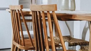 Een eetruimte met een ronde houten tafel en twee houten stoelen.