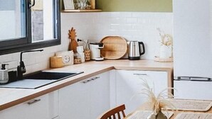 Een moderne keuken met witte kasten, een houten aanrecht en een eethoek met een houten tafel en stoelen.