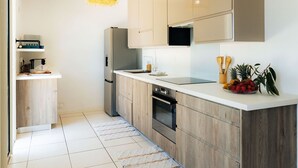 A modern kitchen with wooden cabinets, a stainless steel refrigerator, and a black countertop.