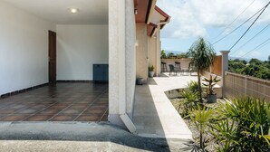 A covered outdoor area with a tiled floor, a door leading inside, and a view of a distant landscape.