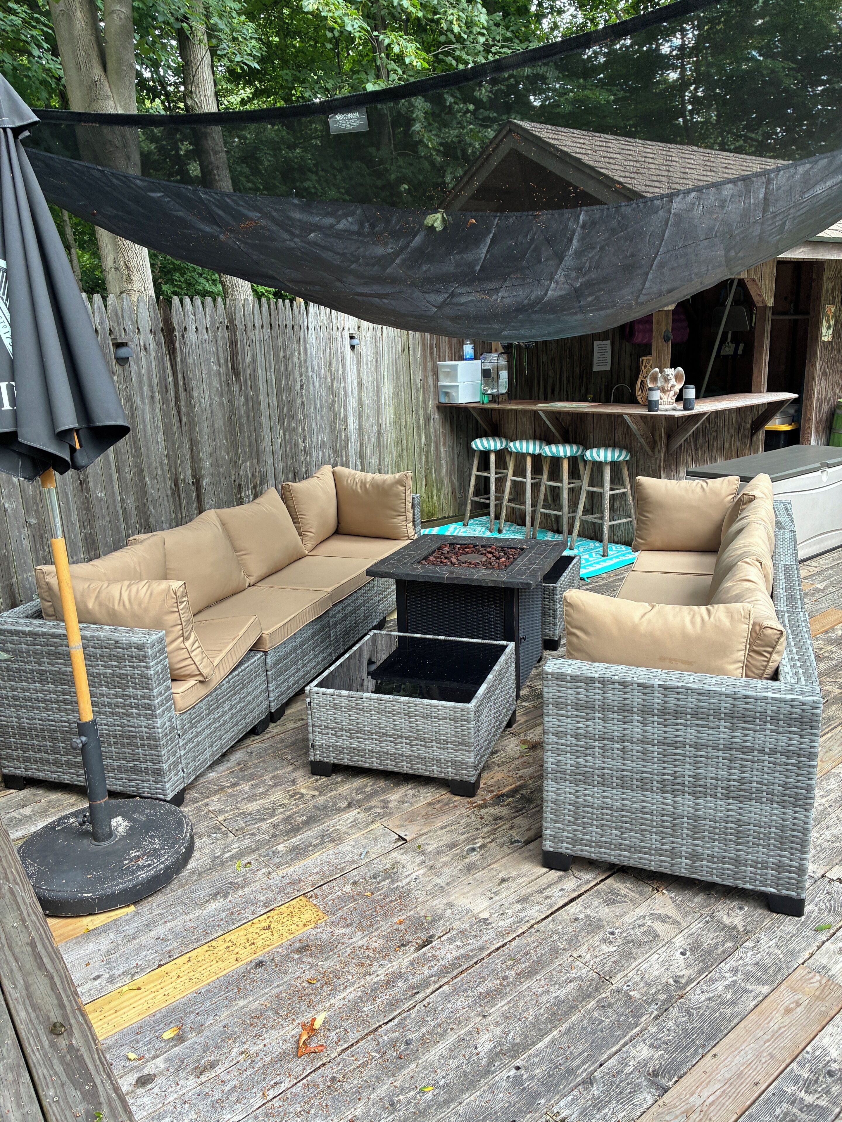A patio with wicker furniture, a table, and a shaded area.
