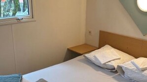 Une chambre d’hôtel avec un lit simple, une table de chevet, une fenêtre et une vue sur l’extérieur.