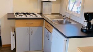 Une cuisine de taille réduite équipée d’une cuisinière à gaz, d’un évier et d’une machine à café.