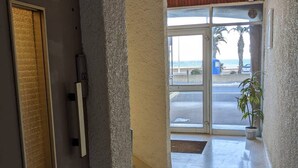 Entrada de hotel con puerta de vidrio que da a un aparcamiento y vistas a la playa.