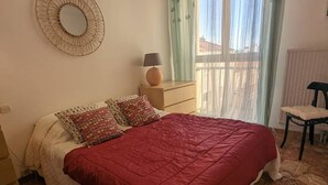 Un dormitorio con una cama, una mesita de noche, una lámpara y una silla.
