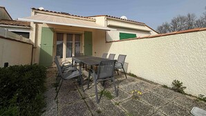 Een terras met een tafel, stoelen, een deur en een muur.