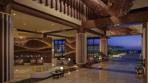 A spacious lobby with a modern design, featuring a seating area with sofas and tables, a reception desk, and large windows offering a view of the cityscape. - Dreams Macao Beach Punta Cana (Punta Cana)