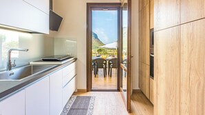 Una cocina moderna con vistas a un balcón, armarios de madera y horno empotrado.