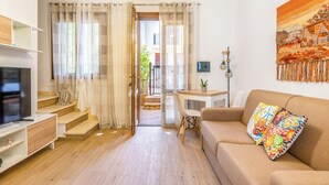 Una sala de estar moderna con sofá, televisor y escalera que lleva a un área exterior.