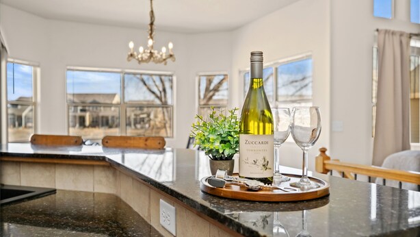 A kitchen island with a bottle of Zucchardi Torrontés wine, two glasses, and a potted plant. - Cabin-style Group Retreat Near Rmnp, Lakes & Golf (Loveland)