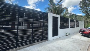 A modern building with a black metal fence, a white door, and a red car parked in front.