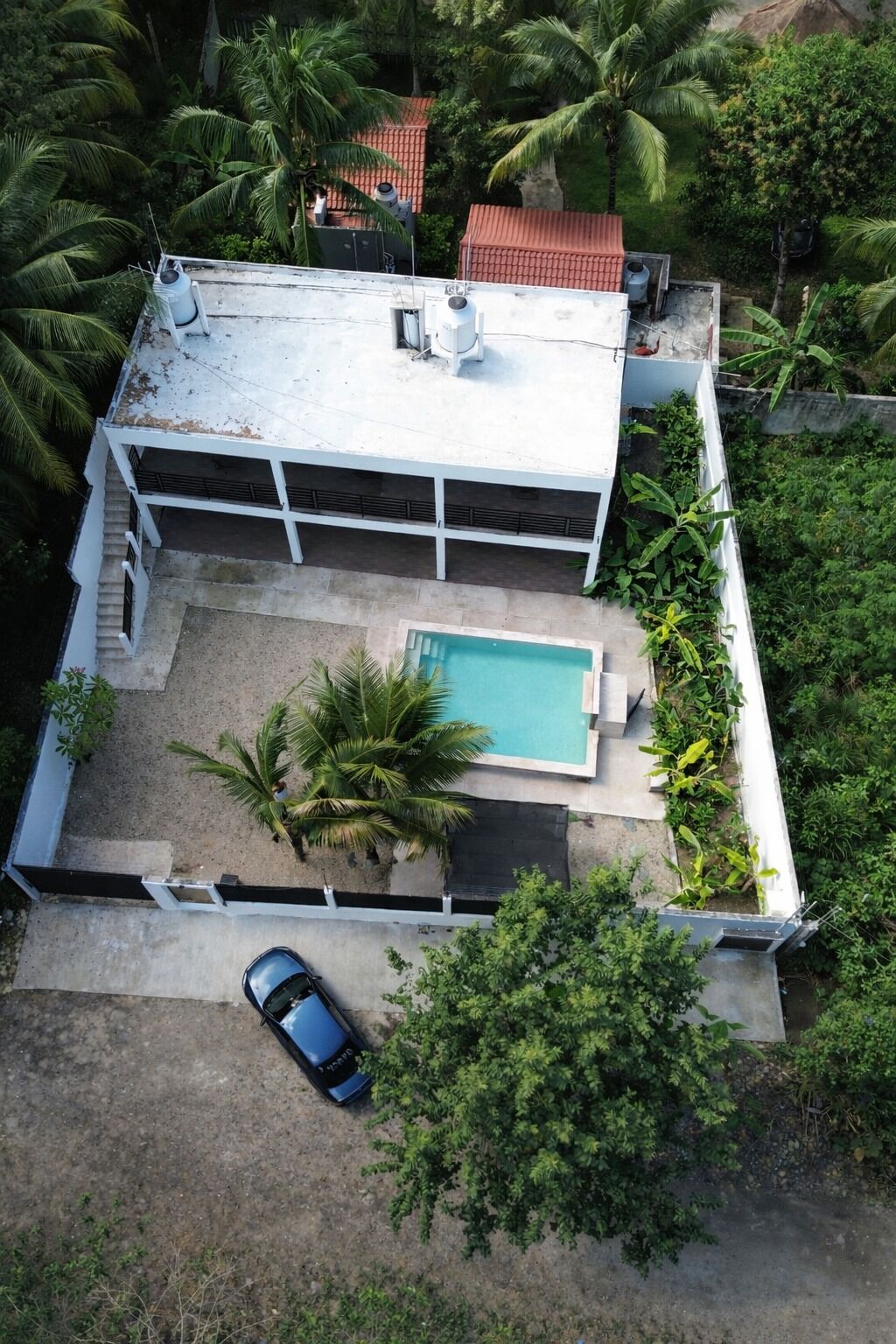 Ein Wohnhaus mit Swimmingpool, einem Auto und üppiger Bepflanzung.
