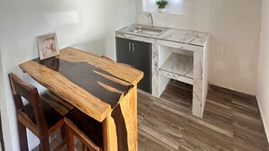 A compact kitchen with a marble countertop, a sink, and a small window with a plant.
