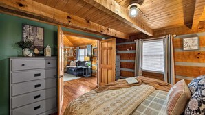 Une pièce confortable avec un lit, une commode et une vue sur une autre pièce où se trouvent un canapé et une cheminée.