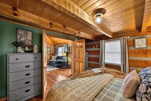 Een gezellige kamer met een bed, een kaptafel en uitzicht op een andere kamer met een bank en een open haard.