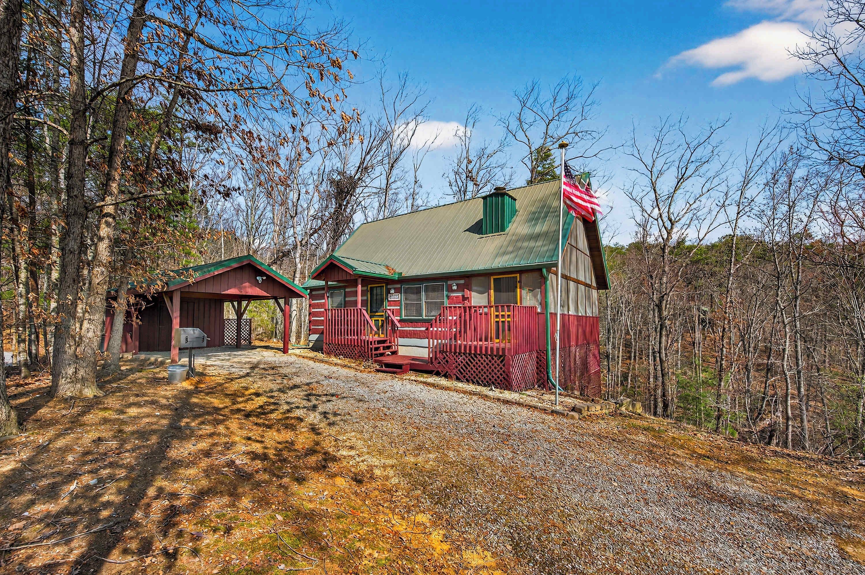 Une cabane à l’extérieur rouge et vert, avec un porche et une boîte aux lettres.