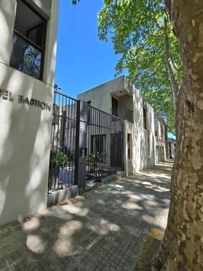 Un immeuble sur lequel on peut lire l’inscription « Hôtel Bastian », avec une entrée fermée par un portail.