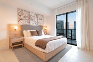 A modern bedroom with a large bed, two bedside tables, a view of the city through a large window, and a balcony. - 41st-Floor Downtown Apt with Bay and Skyline Views 4101 (Miami)