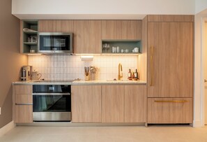 Eine moderne Küche mit Holzschränken, einer eingebauten Mikrowelle, einem Edelstahlbackofen und einer Arbeitsplatte mit verschiedenen Küchenutensilien.