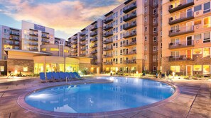 Ein Hotel mit Schwimmbad, mehreren Balkonen und einer gut beleuchteten Fassade.